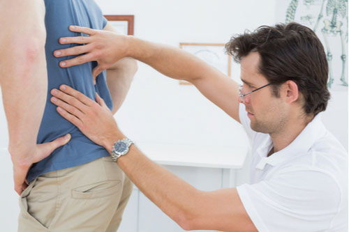 Chiropractor in Greenville SC examines man with back pain- Chiropractor greenville sc, South Carolina Best chiropractor DR at reducing pain