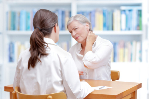 Senior woman with neck pain talking to pain management doctor